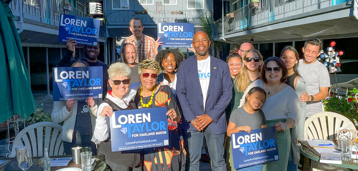 Photo of a group of people including Loren Taylor outside at a House Party; sunny day; people are holding signs that say "Loren Taylor for Mayor"